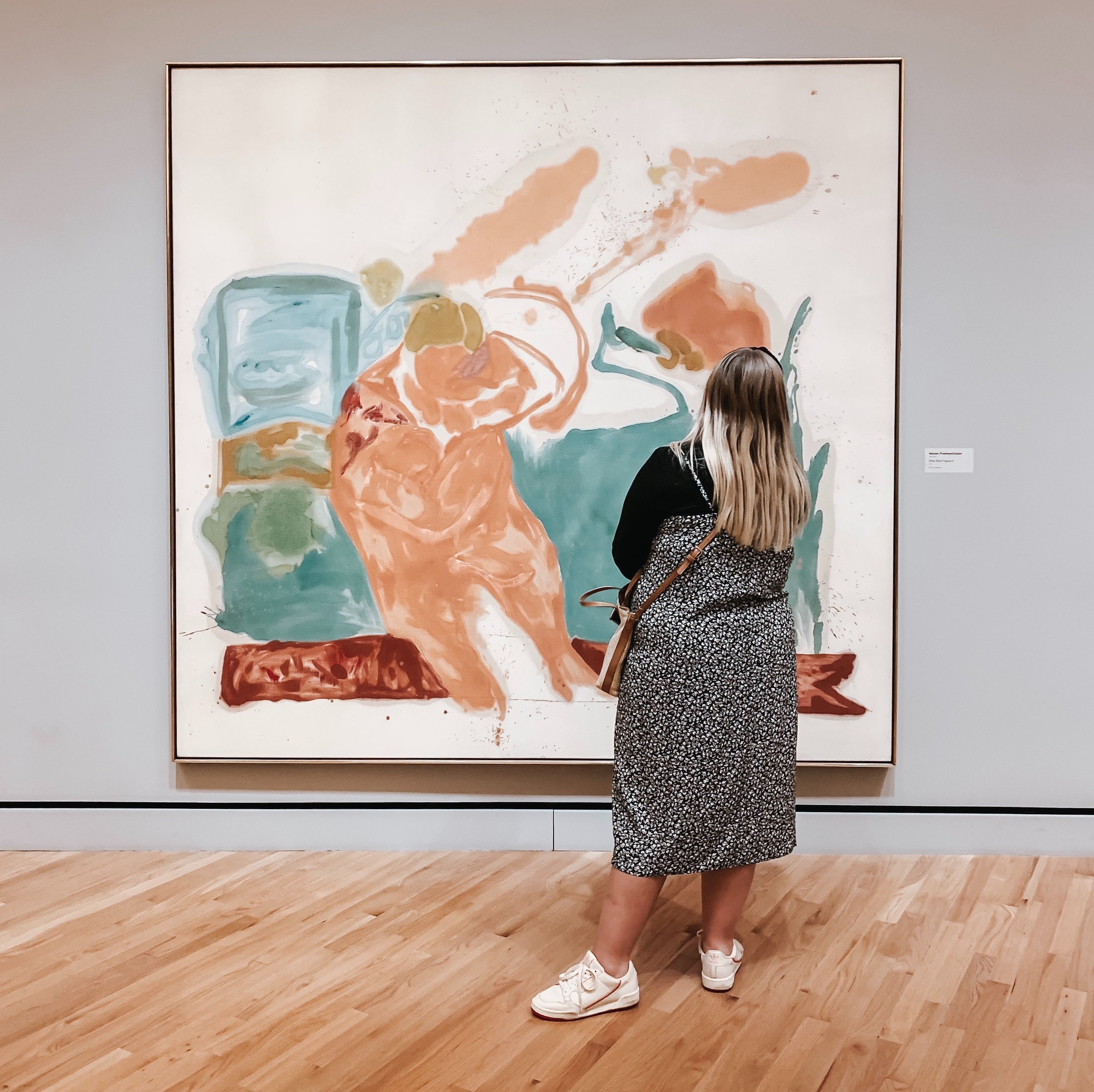 A person examines a large painting in a gallery