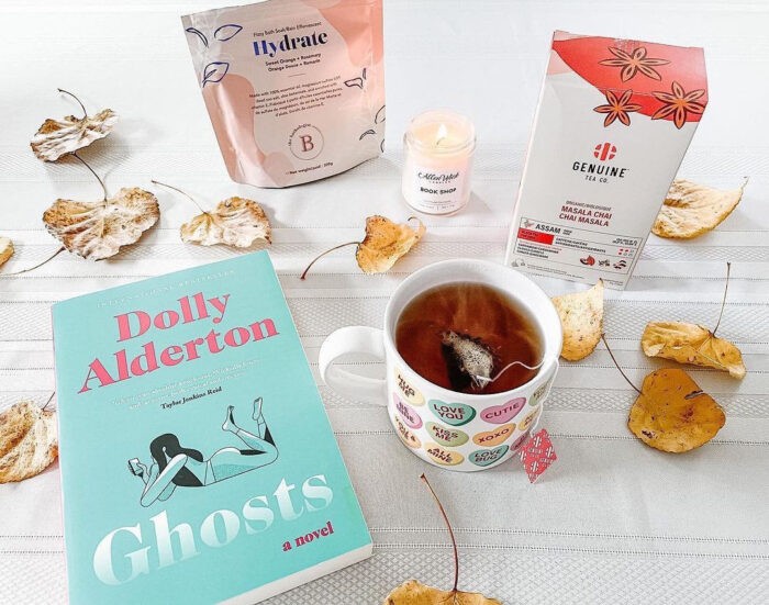 A book titled "Ghosts" arranged on a table with lifestyle items and a mug of tea