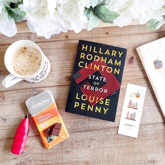 Flat lay of a book, coffee, and chocolate bar laying on a wood table.