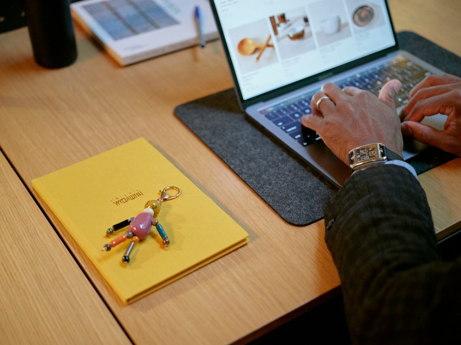 Close up of hands on a computer with a notebook and keychain on the table next to the computer