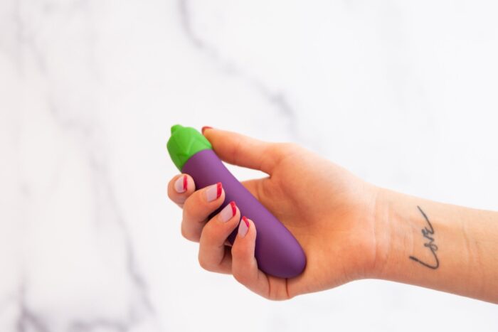 A hand holds a vibrator shaped like an eggplant