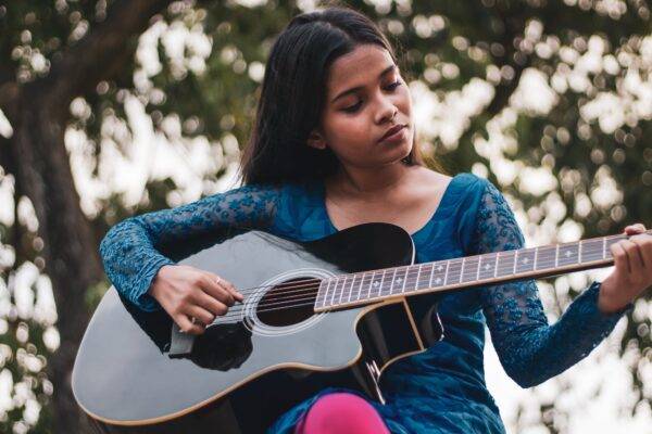 A young person plays the guitar outside