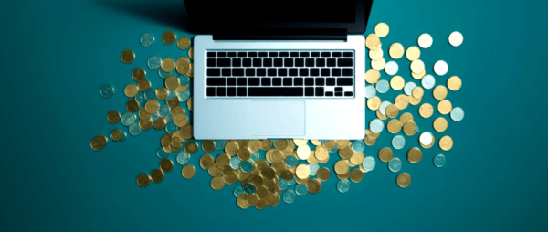 A laptop with coins around it on a blue background: secret websites to make money.