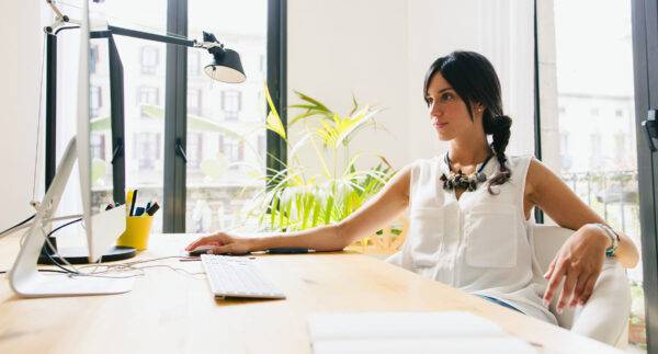 Image of a woman sitting at a desk browsing the internet to find out who owns a domain