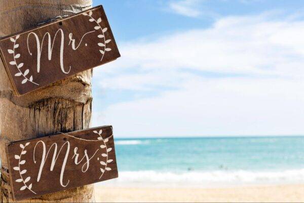 Photo of Mr. and Mrs. wooden signs on a tree at a beach