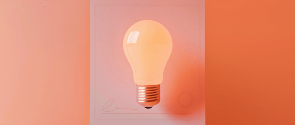 a lightbulb on an orange-pink signed piece of paper representing a patent