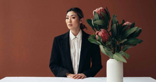 Woman stands behind table with a large vase of flowers on it: how to start a flower business