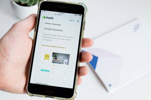 Hand holds a phone open to a screen with information about Shopify Payments