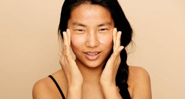 woman putting cream on her cheeks with both hands