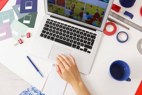 Aerial shot of person sitting at open laptop with office set up.