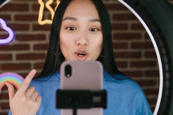 Woman recording a video with a smartphone in front of a ring light