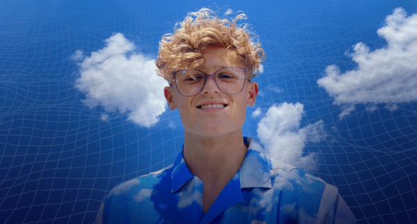 A YouTuber wearing a patterned shirt poses before a computer-generated background.